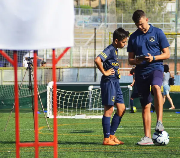 Entrenador analizando datos en tablet junto a un jugador en el campo